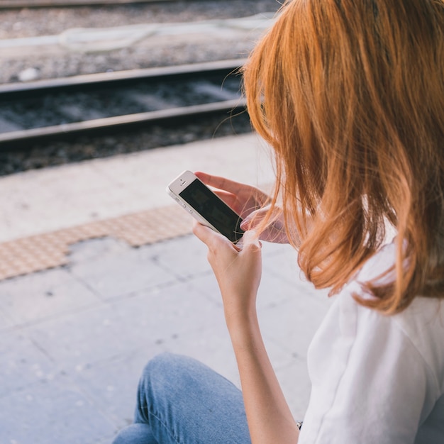 Foto gratuita donna con smartphone sulla stazione ferroviaria