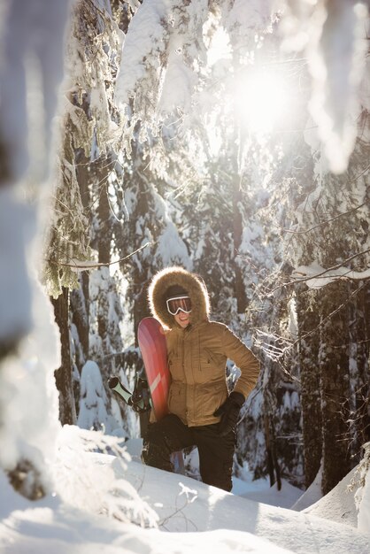 雪山を歩くスノーボードを持つ女性