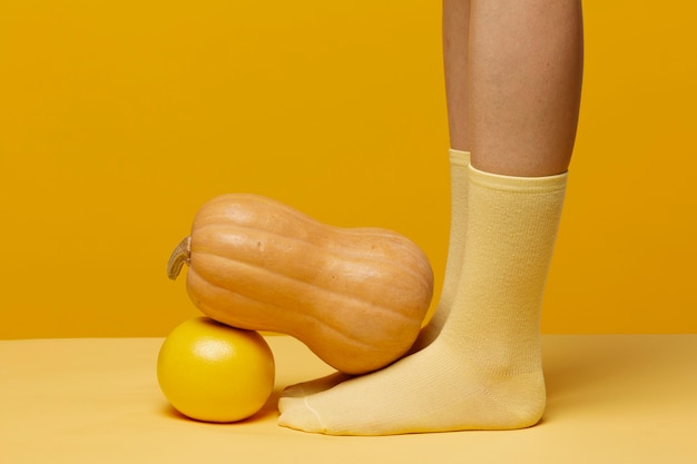 Woman with socks having pumpkin and grapefruit at her feet