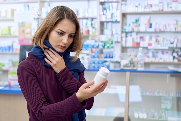 Donna con mal di gola che sceglie le pillole in farmacia