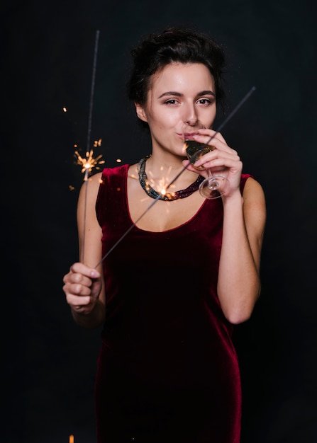 Woman with sparklers drinking champagne from glass 
