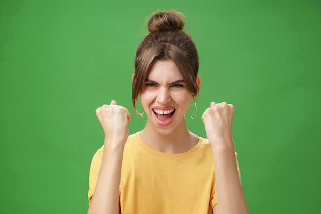 Woman with spirit of winner raising clenched fists smiling excited and supportive cheering being rea...