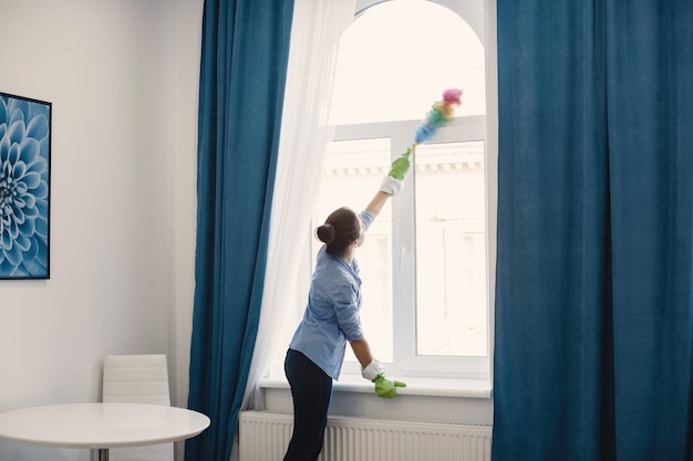 Женщина с губкой и резиновыми перчатками убирает дом