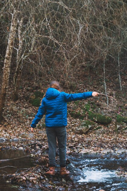 Woman with stick crossing river