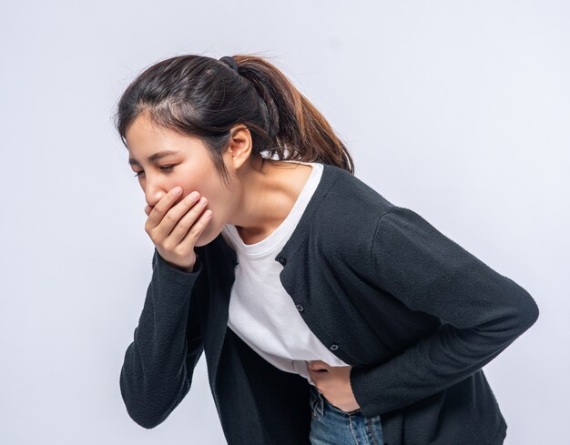 腹痛のある女性は、胃に手を置き、口を覆っています。