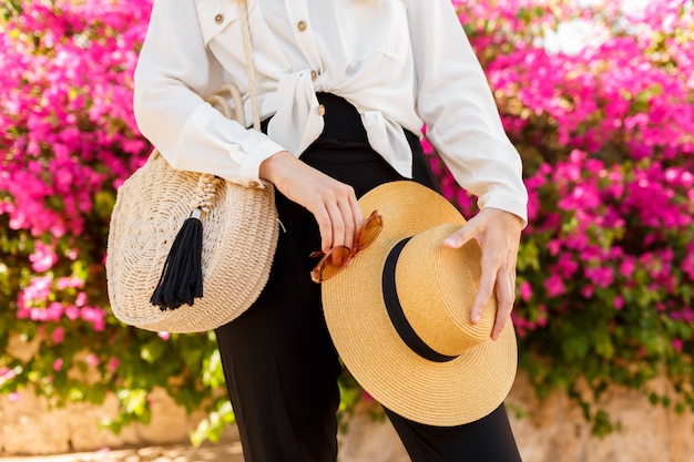 Woman with straw hat posing over pink blooming tree in sunny spring day