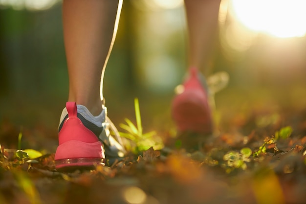 Foto gratuita donna con gambe forti che corre al parco in scarpe da ginnastica sportive