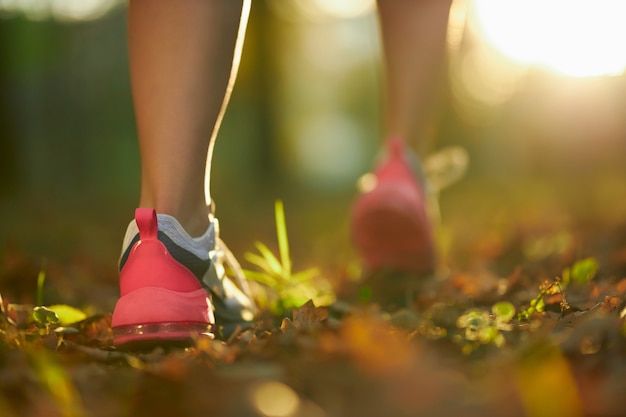 Woman with strong legs running at park in sport sneakers