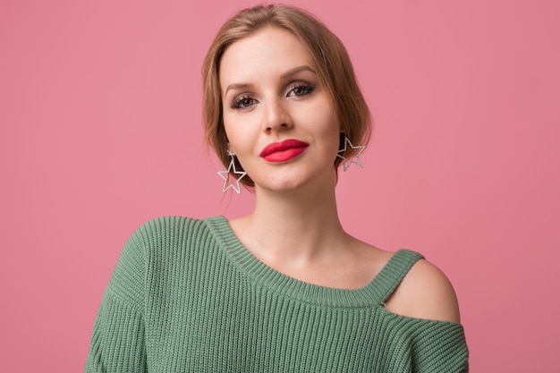 woman with stylish make-up, red lips, green sweater posing on pink