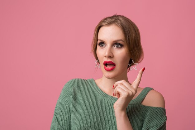 woman with stylish make-up, red lips, green sweater posing on pink