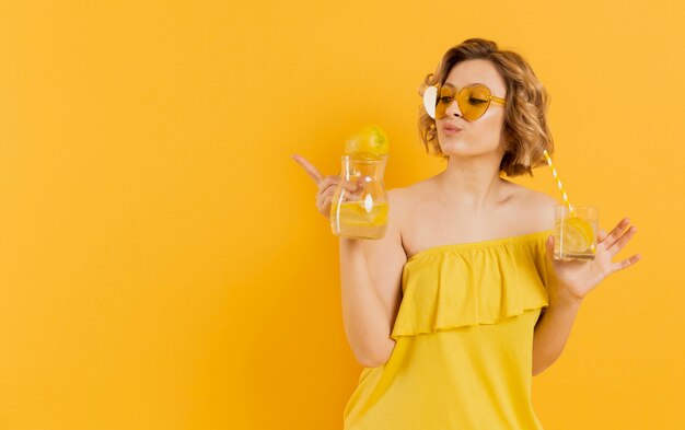 Женщина в темных очках держит стакан лимонада