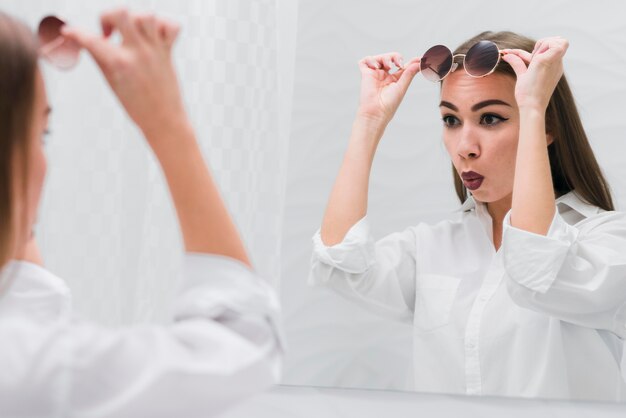 Woman with sunglasses looking in the mirror