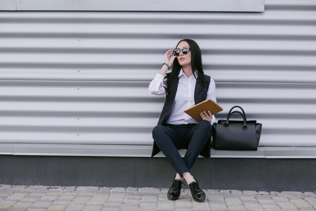 Woman with sunglasses and an orange tablet in hand