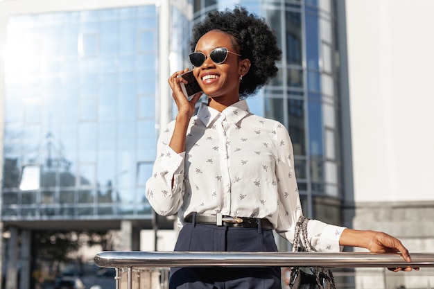 Donna con gli occhiali da sole che parla sopra il telefono