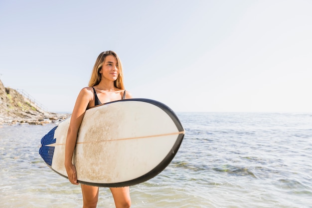 無料写真 ビーチでサーフボードを持つ女性