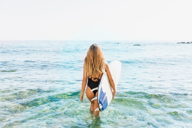 Женщина с доской для серфинга на пляже