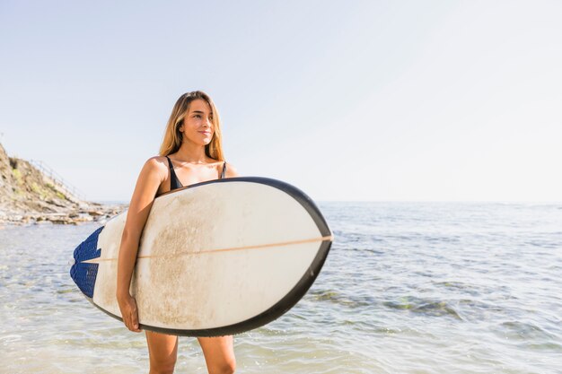 ビーチでサーフボードを持つ女性