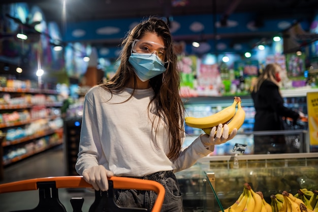 수술 용 마스크를 쓴 여자가 바나나를 사러