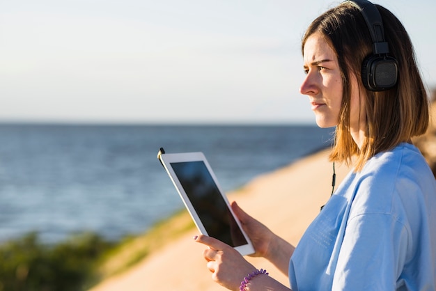 海の近くのタブレットを持つ女性