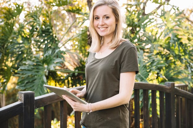 Woman with tablet in park looking at camera