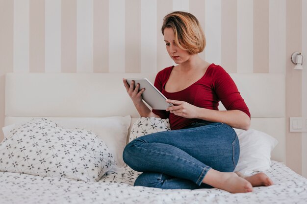 Woman with tablet relaxing on bed