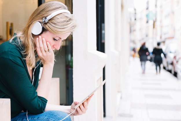 Free photo woman with tablet sitting on street