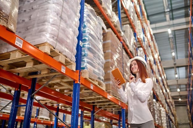 Free photo woman with tablet working near warehouse shelves with cargo