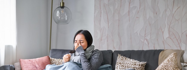 Free photo woman with temperature coughing showing symptoms of flu influenza or cold sitting in warm clothes on