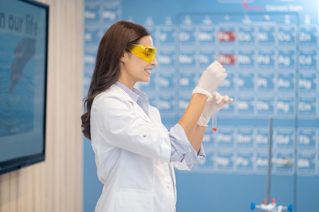 Woman with test tube standing sideways to camera