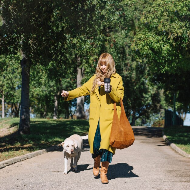 Foto gratuita donna con il thermos che cammina con il cane