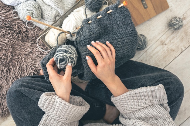 Free photo a woman with threads knits while sitting on the floor at home top view