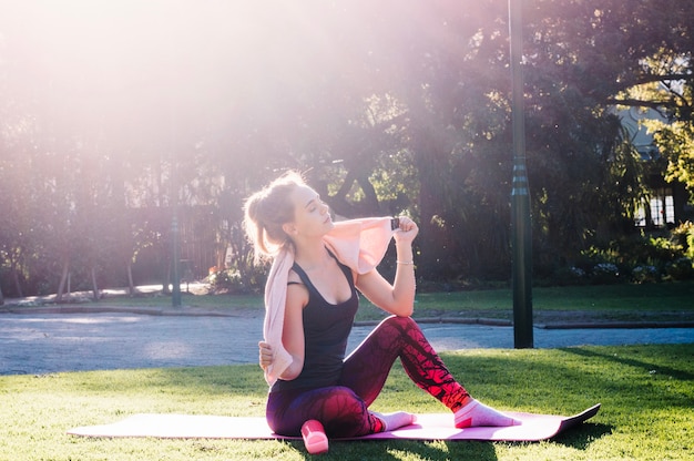 Woman with towel sitting on stretching mat