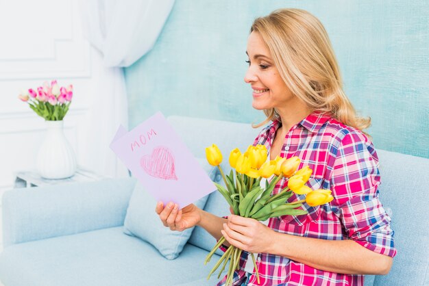 Woman with tulips on couch reading greeting card