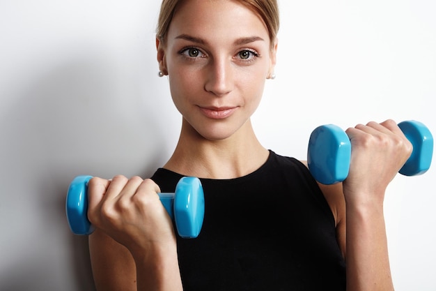 Woman with two barbells looking at camera in studio