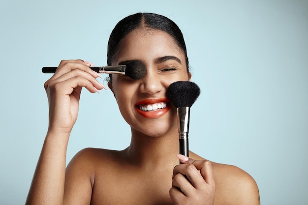 Free photo woman with a two cosmetic brushes is smiling