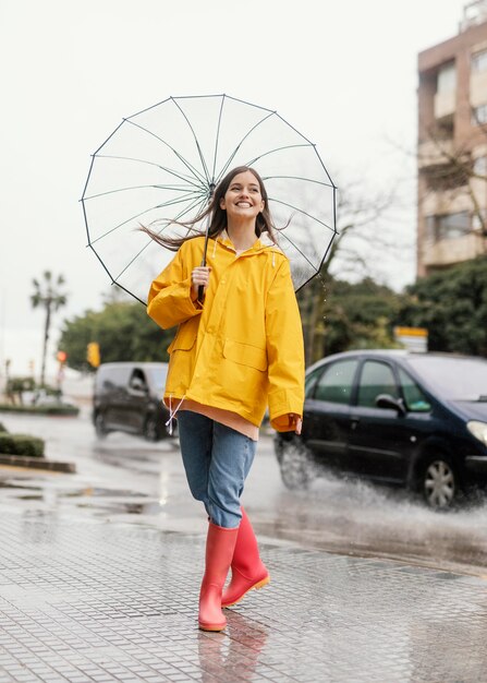 雨の正面図に立っている傘を持つ女性