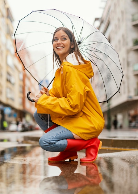 Donna con ombrello in piedi sotto la pioggia vista laterale