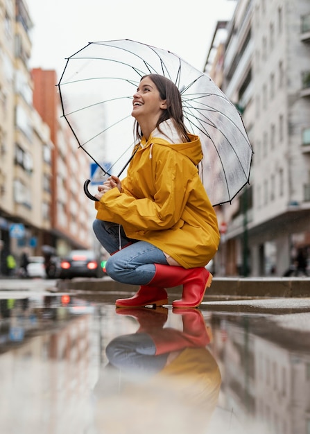 Woman with umbrella standing in the rain side view