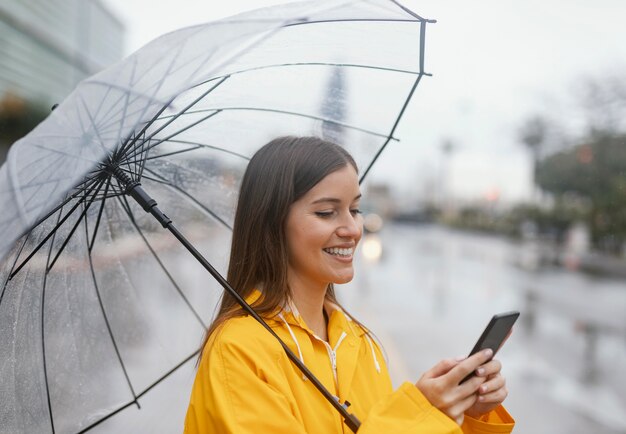 携帯電話を使用して傘を持つ女性