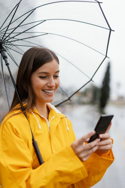 携帯電話を使用して傘を持つ女性