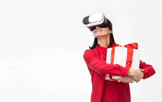 Free photo woman with virtual reality headset holding gift box