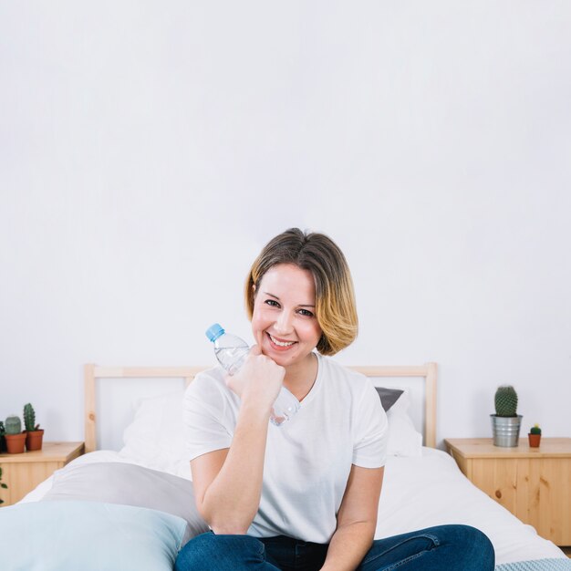 Woman with water bottle on bed