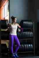 Free photo woman with water bottle leaning on rack