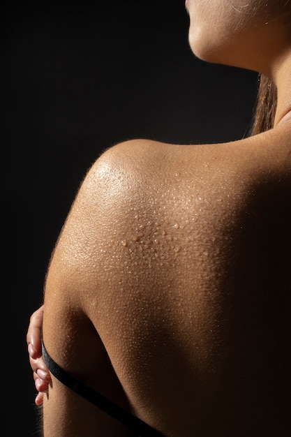 肌の背面図に水滴を持つ女性