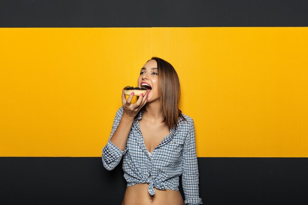 Женщина с белой яркой улыбкой, едят вкусные пончики.