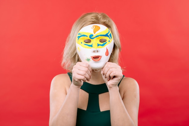 Женщина с белой карнавальной маской в ​​руках