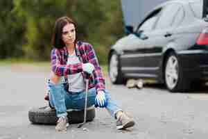 Free photo woman with wrench sitting on tire