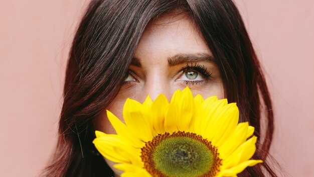 Бесплатное фото Женщина с желтым цветком возле лица