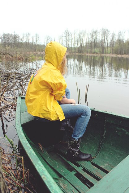 Женщина с желтой куртке сидит в лодке