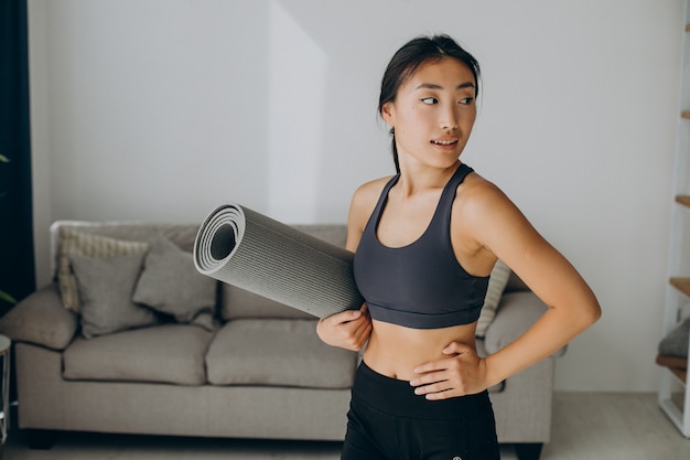 Donna con tappetino da yoga a casa